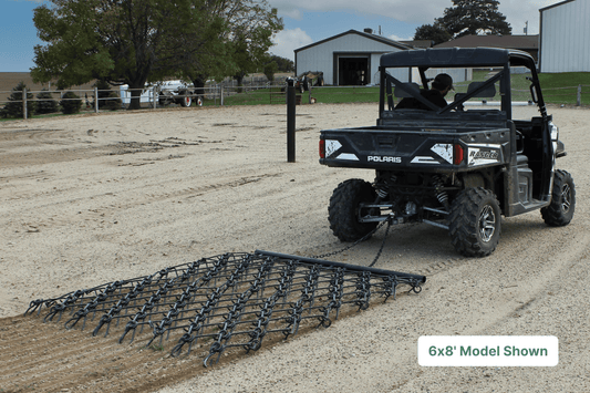 ATV pulling drawbar harrow through gravel farm yard