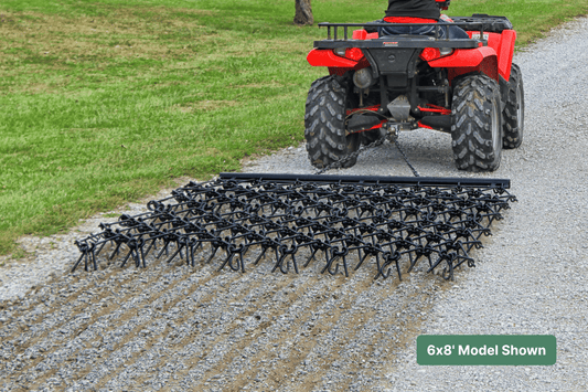 ATV with drawbar harrow on an agricultural gravel path next to grass
