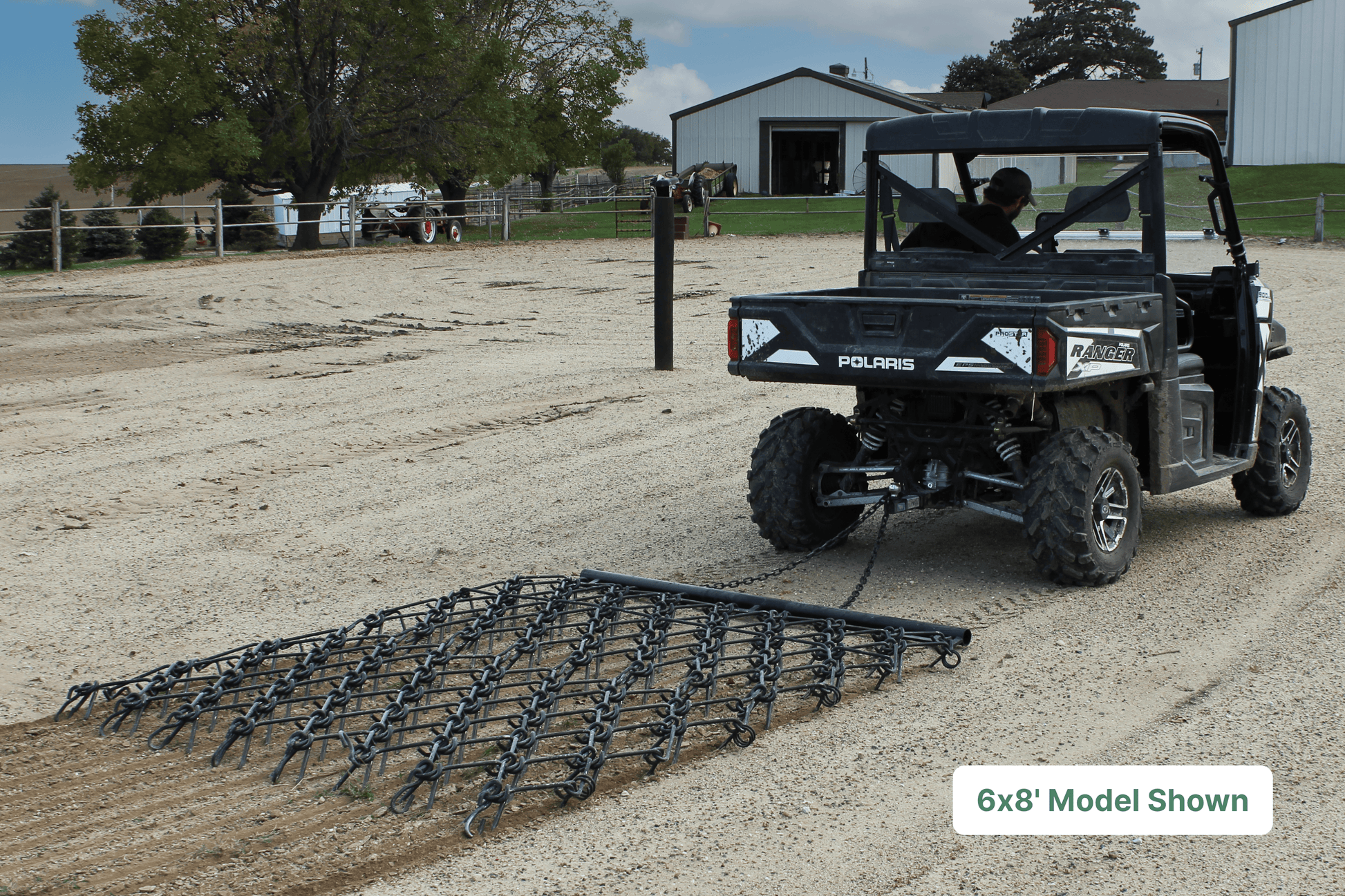 ATV pulling drawbar harrow through gravel farm yard