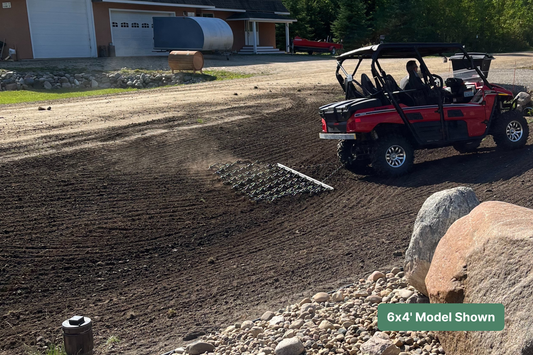 Red utility vehicle tows farm implement in dirt yard